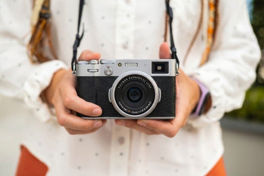 Persona sosteniendo una cámara mirrorless compacta, imagen de portada para guía de fotografía para principiantes.